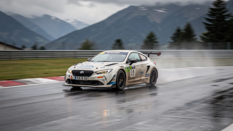 Voiture RC de compétition en pleine course sur un circuit extérieur, éclairage naturel et ambiance alpine en Savoie ou Haute-Savoie.